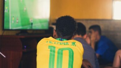 Pessoas assistindo a um jogo de futebol em um escritório.