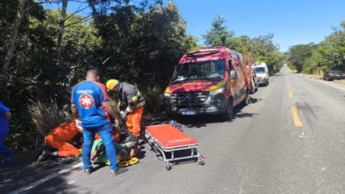 Carro acidentado em ribanceira com equipes de resgate ao redor.