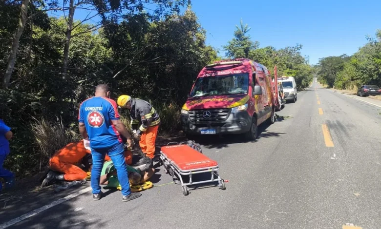 Carro acidentado em ribanceira com equipes de resgate ao redor.