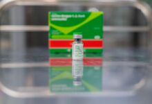 Frasco de vacina contra a dengue em fundo neutro.