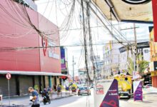 Funcionário da prefeitura inspeciona fios soltos em poste de rua em Goiânia.