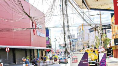 Funcionário da prefeitura inspeciona fios soltos em poste de rua em Goiânia.