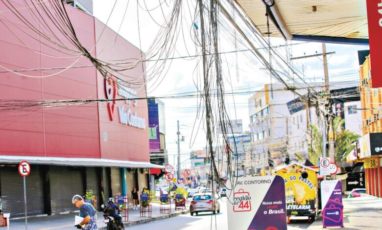 Funcionário da prefeitura inspeciona fios soltos em poste de rua em Goiânia.