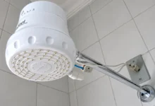 Chuveiro elétrico em funcionamento, com vapor visível.
