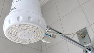 Chuveiro elétrico em funcionamento, com vapor visível.