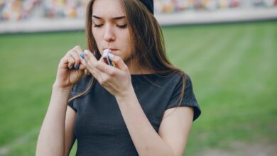 Adolescente segurando cigarro eletrônico em ambiente urbano.