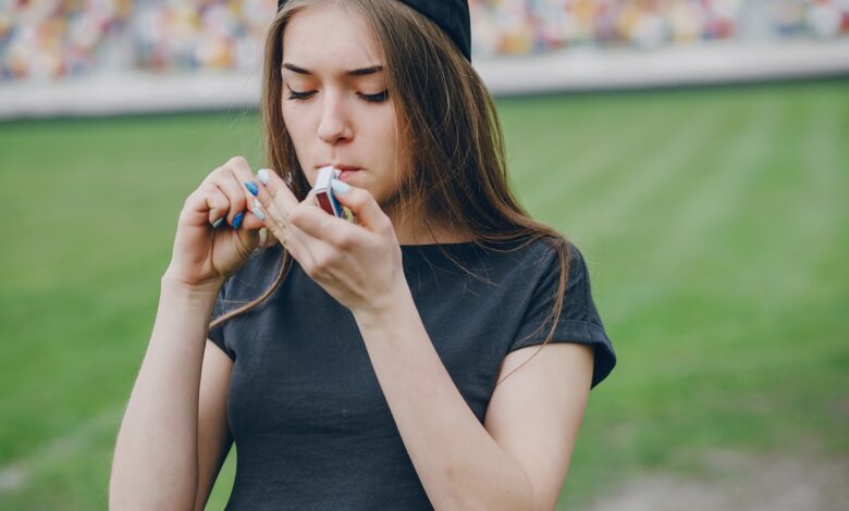 Adolescente segurando cigarro eletrônico em ambiente urbano.