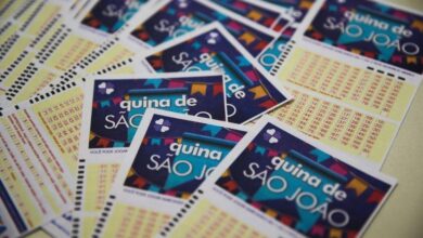 Bilhete de loteria da Quina de São João sendo preenchido em uma mesa.