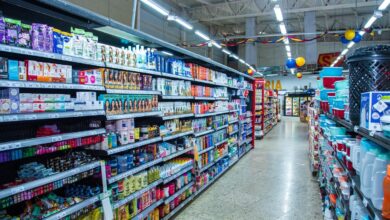 Imagem de um supermercado em operação, com carrinhos de compras e clientes.
