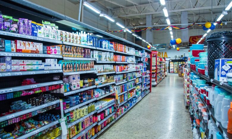 Imagem de um supermercado em operação, com carrinhos de compras e clientes.