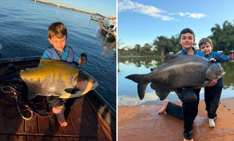 Dois irmãos goianos segurando um peixe grande, capturado durante pescaria.