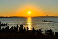 Pessoas relaxando em uma praia às margens do Rio Araguaia em um dia ensolarado.