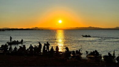 Pessoas relaxando em uma praia às margens do Rio Araguaia em um dia ensolarado.