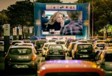 Carros estacionados assistindo a uma sessão de cinema drive-in à noite.