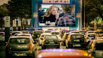 Carros estacionados assistindo a uma sessão de cinema drive-in à noite.