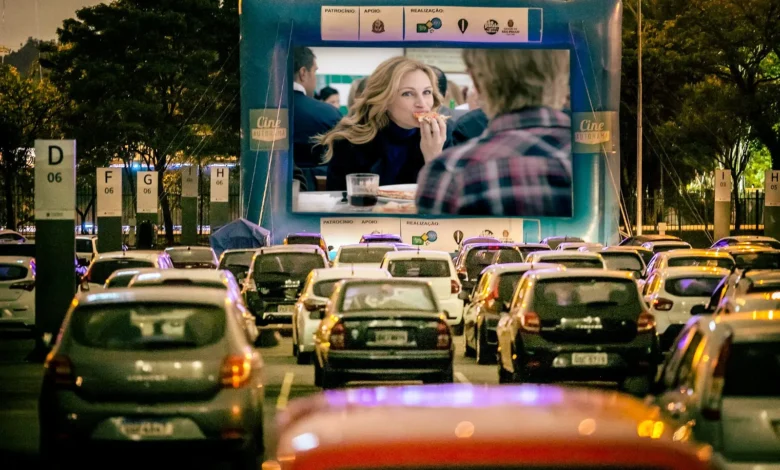 Carros estacionados assistindo a uma sessão de cinema drive-in à noite.