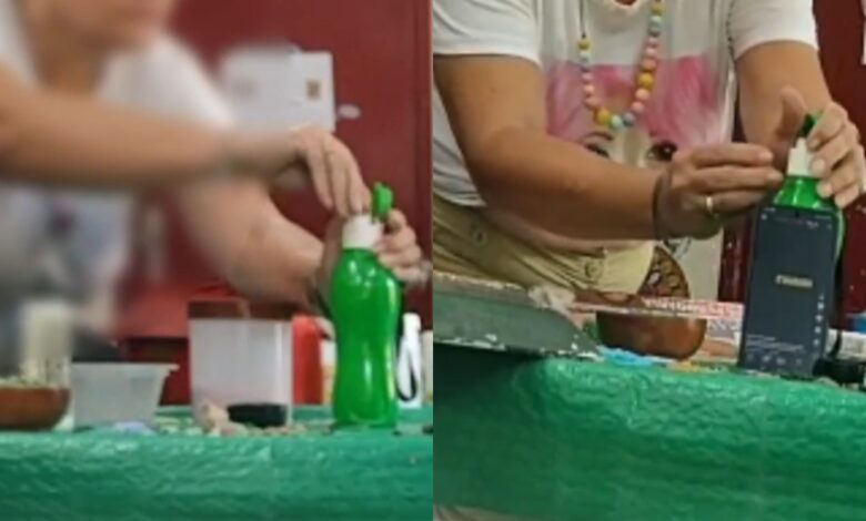 Mulher filmada colocando substância em garrafa de água.