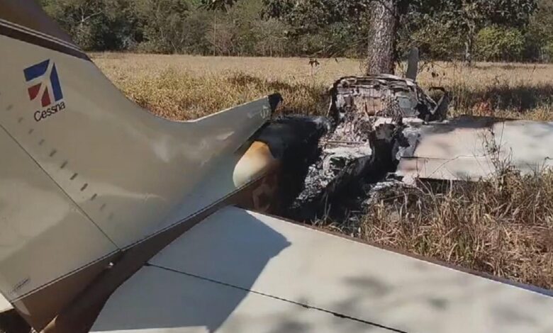 Avião pequeno em campo aberto próximo a área rural.