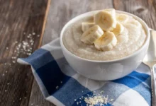 Tigela de mingau proteico com frutas e sementes em uma mesa.
