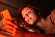 Pessoa usando celular na cama à noite.