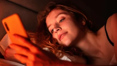 Pessoa usando celular na cama à noite.