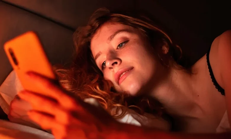 Pessoa usando celular na cama à noite.