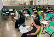 Pessoas preenchendo formulários de inscrição para curso preparatório.