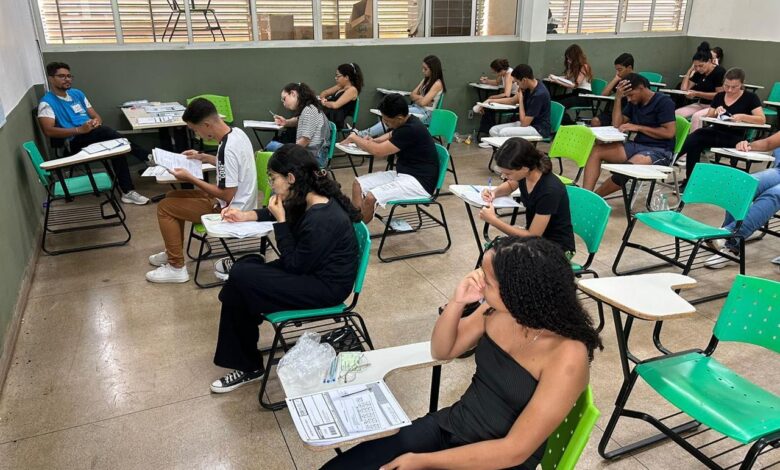 Pessoas preenchendo formulários de inscrição para curso preparatório.