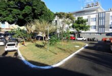 Praça urbana em Goiânia com árvores e bancos.