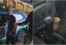 Motorista sorrindo enquanto é preso por embriaguez ao volante.