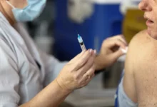 Profissional de saúde aplicando vacina em criança em UBS.