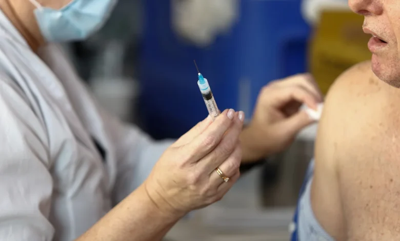 Profissional de saúde aplicando vacina em criança em UBS.