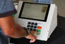 Urnas eletrônicas sendo preparadas para as eleições de 2026, destacando a nova interface e recursos de acessibilidade.