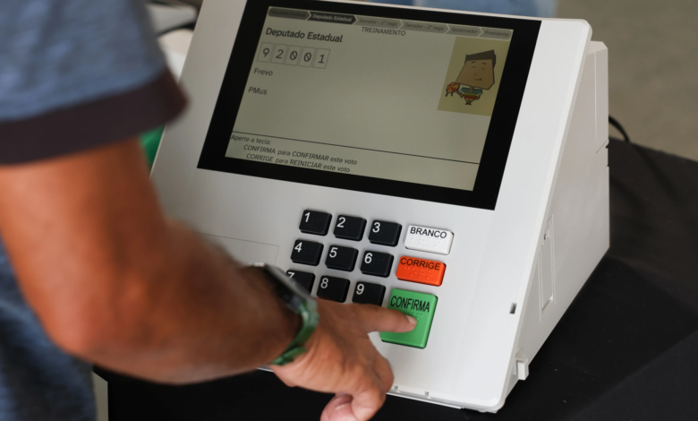 Urnas eletrônicas sendo preparadas para as eleições de 2026, destacando a nova interface e recursos de acessibilidade.