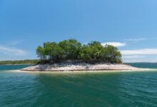 Imagem aérea da Ilha do Amor em Goiás, mostrando águas cristalinas e vegetação ao redor.