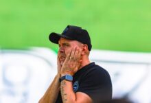 Jogadores do Goiás em campo com faixas pretas nos braços durante protesto.
