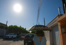 Termômetro marcando alta temperatura em uma rua movimentada de Goiás.