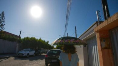 Termômetro marcando alta temperatura em uma rua movimentada de Goiás.