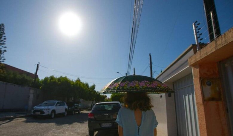 Termômetro marcando alta temperatura em uma rua movimentada de Goiás.