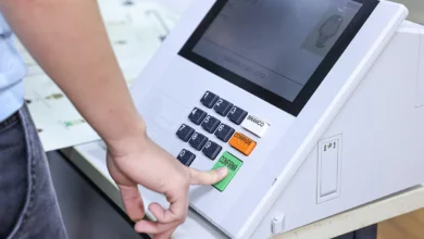 Eleitores brasileiros em seção de votação com urna eletrônica.