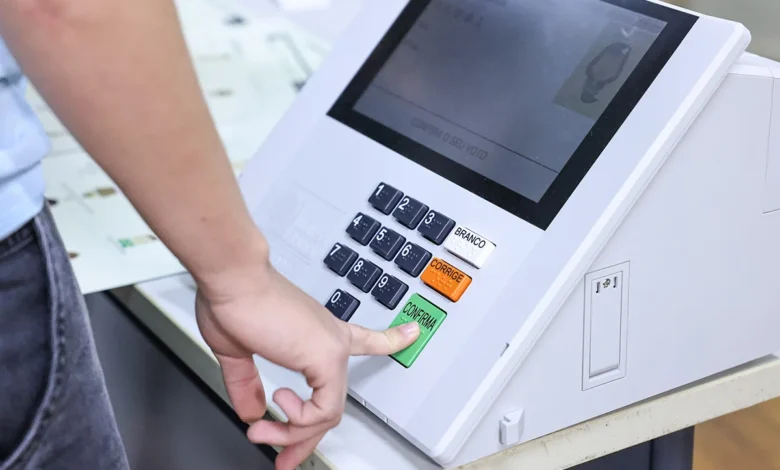 Eleitores brasileiros em seção de votação com urna eletrônica.