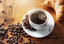 Grãos de café arábica e conilon em uma mesa de madeira.