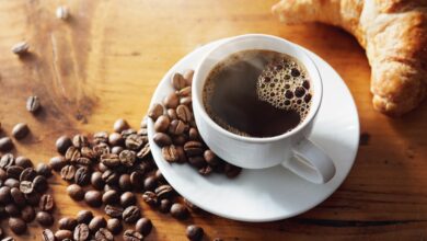 Grãos de café arábica e conilon em uma mesa de madeira.