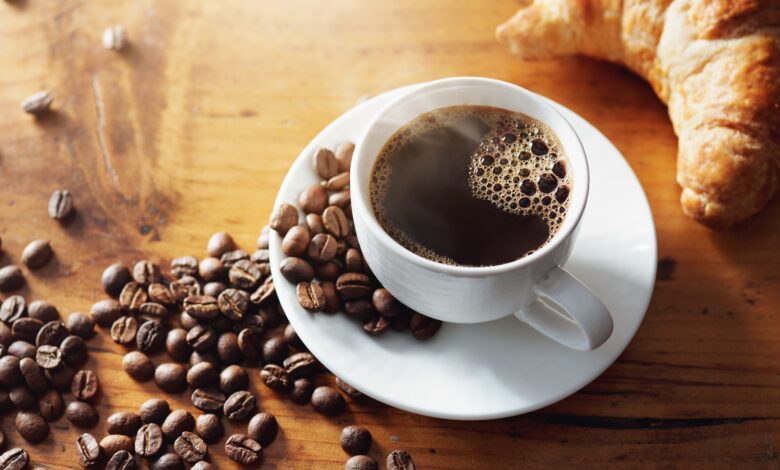 Grãos de café arábica e conilon em uma mesa de madeira.