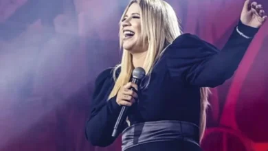 Marília Mendonça em um show, segurando o microfone.