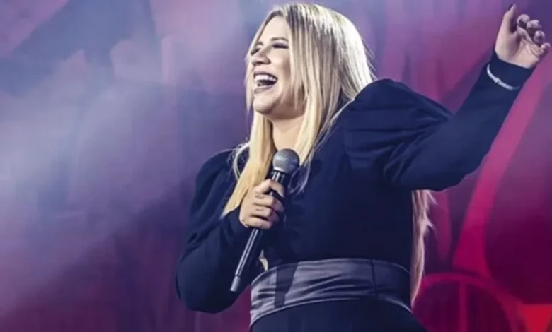 Marília Mendonça em um show, segurando o microfone.