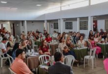 Pessoa analisando documentos de compra de imóvel em uma mesa com maquete de casa.